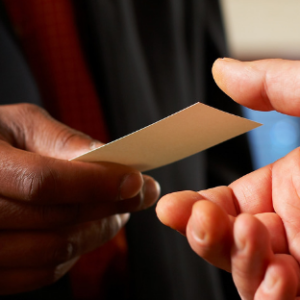 A hand passing a business card to another during networking